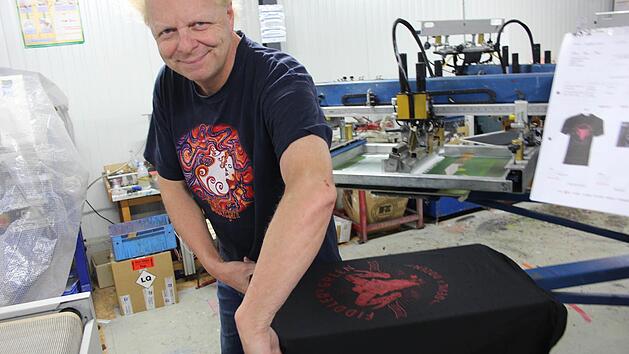 Atze Bauer zieht ein T-Shirt von der Maschine ab, bevor es in den Trockner gelegt wird. Foto: Yannick Hupfer