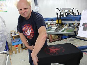 Atze Bauer zieht ein T-Shirt von der Maschine ab, bevor es in den Trockner gelegt wird. Foto: Yannick Hupfer