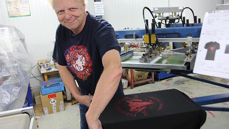 Atze Bauer zieht ein T-Shirt von der Maschine ab, bevor es in den Trockner gelegt wird. Foto: Yannick Hupfer