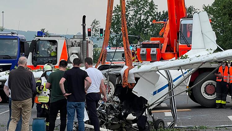 Einsatzkr&auml;fte der Feuerwehr haben mit Hilfe eines Krans das Wrack eines abgest&uuml;rzten Kleinflugzeugs aus der B&ouml;schung einer Stra&szlig;e geborgen. Bei dem Absturz waren zwei Menschen ums Leben gekommen. Foto: Michael Seeboth/dpa