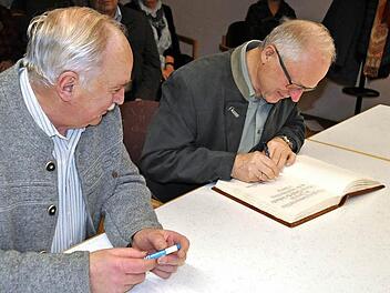 Der ehemalige Kreisrat Gerhard Eller (rechts) und der ehemalige Bürgermeister Hermann Martin beim Eintrag in das Goldene Buch der Gemeinde Pfarrweisach. Foto: Simon Albrecht