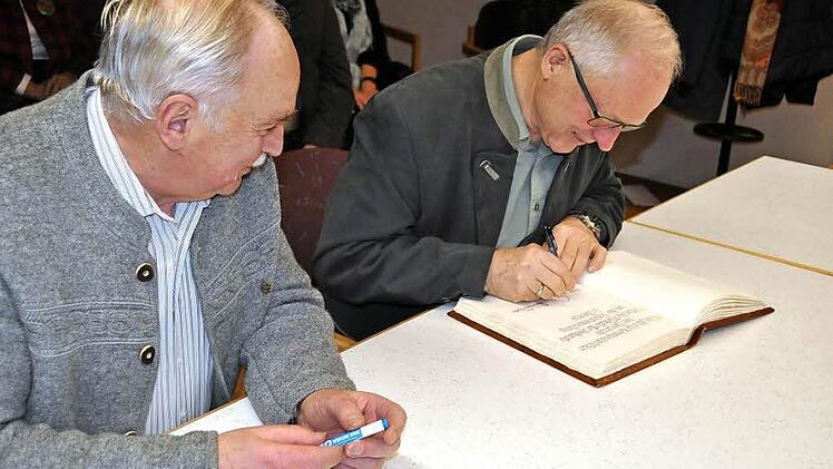 Der ehemalige Kreisrat Gerhard Eller (rechts) und der ehemalige Bürgermeister Hermann Martin beim Eintrag in das Goldene Buch der Gemeinde Pfarrweisach. Foto: Simon Albrecht
