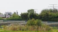 Hinter dem Grünstreifen stehen die Solarmodule - ab und zu blitzen zwischen den Büschen die Führerhäuser der Lkw auf.