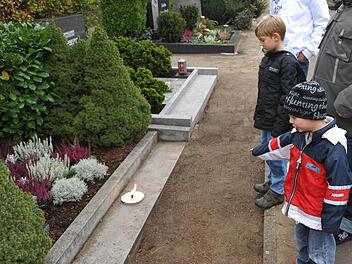 Kinder stehen an einem Grab auf dem Bamberger Hauptfriedhof.  Foto:  Ronald  Rinklef