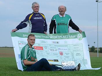 TSV-Vorsitzender Nico Rogge (sitzend), Paul Küthe (Mitglied Sportplatz-Kommission) und Architekt Burkard Kuhn (rechts) mit der Sponsoren-Tafel und dem Spaten als Symbol für den Sportplatz-Neubau. Foto: Jürgen Schmitt