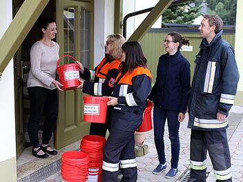 Die Aktiven der Feuerwehr Tschirn mit (von links) Gina Holzmann, Laura Geisler, Vorsitzender Julia Barnickel und Kommandant Michael Schnappauf zogen von Haus zu Haus und verteilten, wie hier an Sabrina Ringelberg ihre Haushalts-Löscheimer. Foto: Michael Wunder