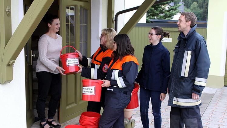 Die Aktiven der Feuerwehr Tschirn mit (von links) Gina Holzmann, Laura Geisler, Vorsitzender Julia Barnickel und Kommandant Michael Schnappauf zogen von Haus zu Haus und verteilten, wie hier an Sabrina Ringelberg ihre Haushalts-Löscheimer. Foto: Michael Wunder