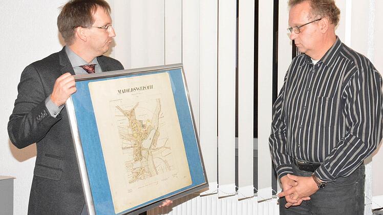 Bürgermeister Wolfram Thein (links) verabschiedet Gerald Welz (rechts), der dem Marktgemeinderat 18 jahre lang angehört hat, mit einem alten Stich von Maroldsweisach. Foto: Schmidt