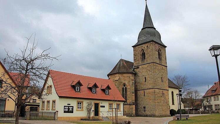 Der gepflasterte Platz vor der Kirche ist ein Ergebnis der Dorferneuerung und eine besonders schöne Stelle im Ort. Vorne, im Jugendheim, war einst die Gemeindeverwaltung untergebracht.