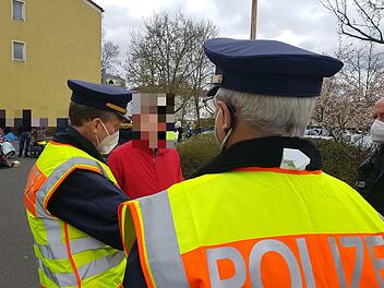 Johann Fischer (Name geändert) steht unmaskiert zwischen zwei Polizisten. Links im Bild Dienststellenleiter Stefan Haschke. Foto: Susanne Will