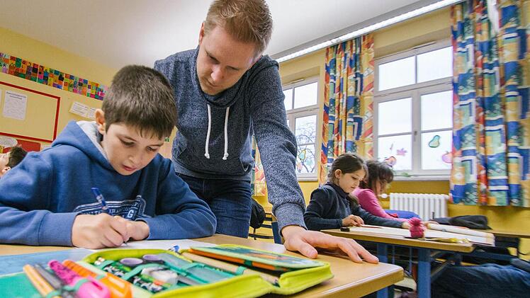 Einmal die Woche unterstützt Patrick Löhr (Mitte) die Hausaufgabenbetreuung und hilft Schülern wie dem mit seinen Eltern aus Tschetschenien geflohenen Mayrbek (zehn Jahre), die gestellten Aufgaben zu verstehen und zu bearbeiten. Foto: Marian Hamacher