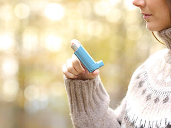 Eine Frau hält ein Asthma-Medikament in der Hand.