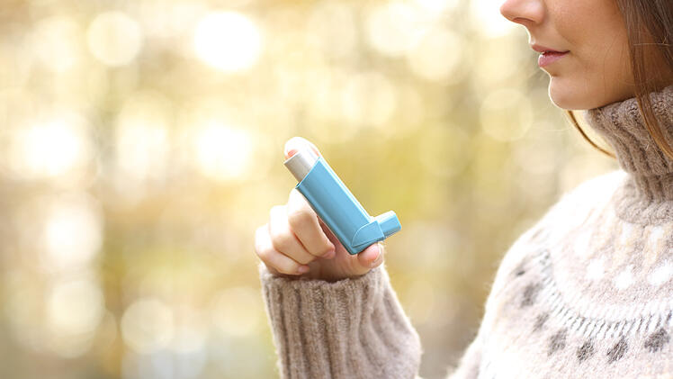 Eine Frau hält ein Asthma-Medikament in der Hand.