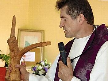 Pfarrer Andreas Hornung und das von Monika Wölfel geschnitzte Kreuz. Letzeres hängt im neuen Sterberaum.  Foto: Petra Malbrich