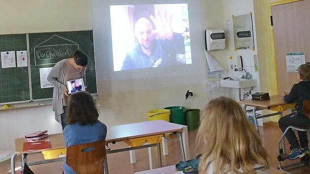 Aufmerksam verfolgen die Schüler der Klasse 3a mit Lehrerin Lena Hannig die Worte ihres Schulpaten Dominic Herrmann, der per Videoschaltung auf der Leinwand im Klassenzimmer zu sehen ist.  Foto: K.- H. Hofmann