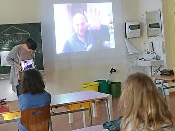 Aufmerksam verfolgen die Schüler der Klasse 3a mit Lehrerin Lena Hannig die Worte ihres Schulpaten Dominic Herrmann, der per Videoschaltung auf der Leinwand im Klassenzimmer zu sehen ist.  Foto: K.- H. Hofmann