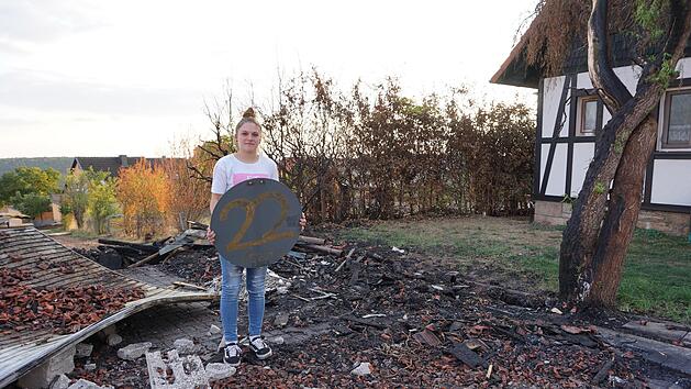 Pia Schlereth in den Tr&uuml;mmern der Scheune. Doch das zarte Gr&uuml;n am Baum zeigt, dass das Leben nach dem Gro&szlig;brand weiter geht. Das Schild mit der 22 erinnert an ihren Geburtstag, den sie am Wochenende zuvor in der Scheune feierte.