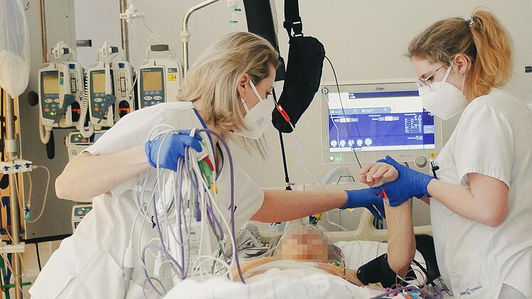 Zwei Krankenpflegerinnen &uuml;berwachen die Werte einer Intensivpatientin. Die ganze Zeit m&uuml;ssen sie dabei auf dutzende Schl&auml;uche aufpassen.