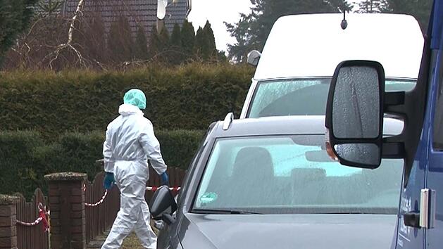 Ein Kriminalpolizist in einem weißen Overall geht vor einem Einfamilienhaus zu einem Einsatzfahrzeug. Eine junge Frau ist umgebracht worden. Nach dem Hinweis eines Mannes auf eine tote Frau in einem Wohnhaus entdeckten Beamte den Leichnam in der Nacht zum 22.03.2018. Foto: TNN/dpa