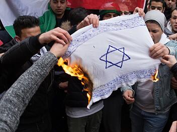 Teilnehmer einer Demonstration verbrennen am 10.12.2017 eine selbstgemalte Fahne mit einem Davidstern in Berlin im Stadtteil Neuk&ouml;lln.  Foto: J&uuml;disches Forum f&uuml;r Demokratie und gegen Antisemitismus e.V./dpa