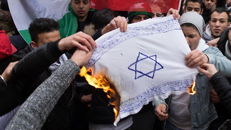 Teilnehmer einer Demonstration verbrennen am 10.12.2017 eine selbstgemalte Fahne mit einem Davidstern in Berlin im Stadtteil Neuk&ouml;lln.  Foto: J&uuml;disches Forum f&uuml;r Demokratie und gegen Antisemitismus e.V./dpa