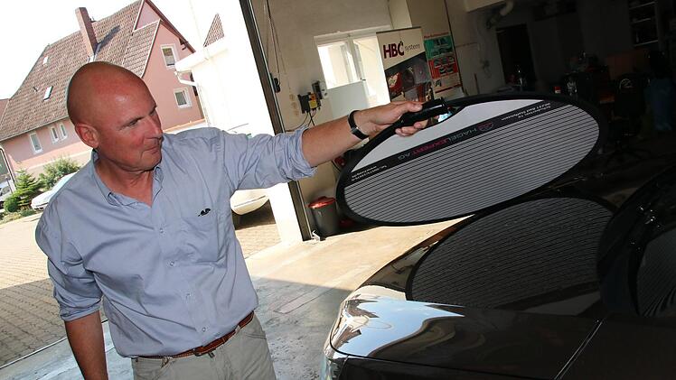 Ulrich Gebauer prüft mit dem Dellenspiegel, wie stark die Motorhaube dieses Fahrzeugs beschädigt ist.Matthias Einwag