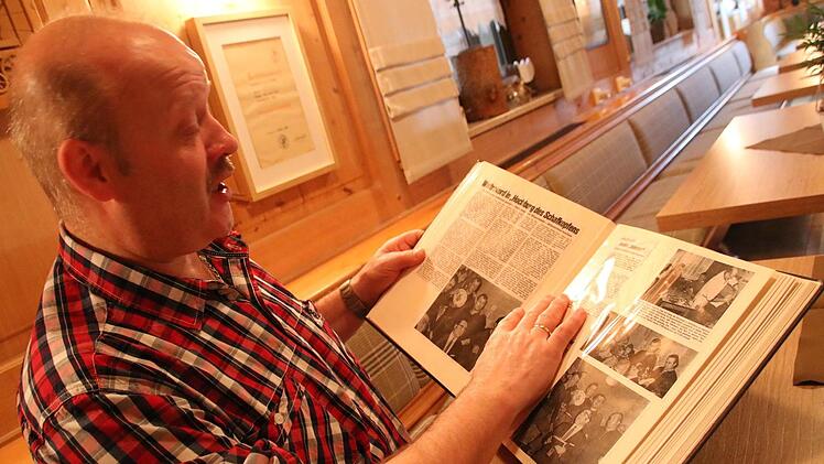 Der Schwabthaler Gastwirt Andreas Pfarrdrescher blättert in einem Album mit Zeitungsartikeln des Dauerschafkopfturniers, an dem sein Vater Georg einst teilgenommen hat.Matthias Einwag