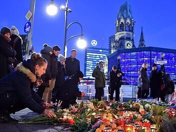 Eine junge Frau zündet am 21.12.2016 in Berlin unweit der Stelle des Anschlags auf dem Weihnachtsmarkt am Breitscheidplatz Kerzen an. Bei einem Anschlag am 19.12.2016 mit einem Lastwagen auf einen Weihnachtsmarkt an der Gedächtniskirche wurden zwölf Menschen getötet und rund 50 verletzt. Foto: Britta Pedersen/dpa