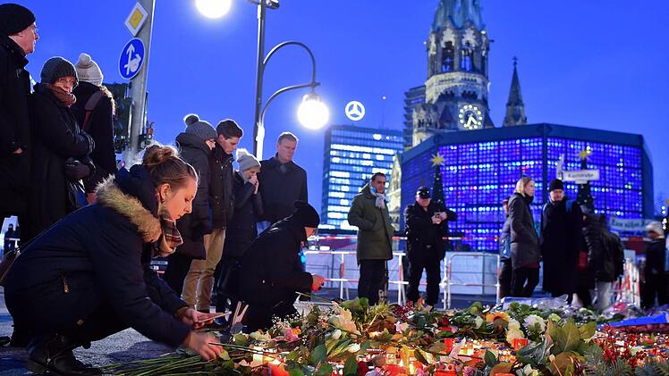 Eine junge Frau zündet am 21.12.2016 in Berlin unweit der Stelle des Anschlags auf dem Weihnachtsmarkt am Breitscheidplatz Kerzen an. Bei einem Anschlag am 19.12.2016 mit einem Lastwagen auf einen Weihnachtsmarkt an der Gedächtniskirche wurden zwölf Menschen getötet und rund 50 verletzt. Foto: Britta Pedersen/dpa