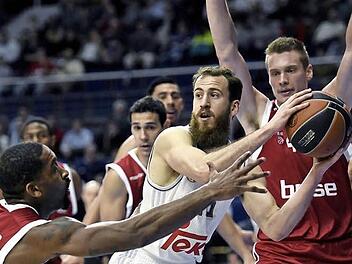 Brad Wanamaker (l.) und Leon Radosevic nehmen Sergio Rodriguez in die Zange. In der zweiten Hälfte drehte der Real-Star dann aber auf und rettete seiner Mannschaft den Sieg. Foto: dpa