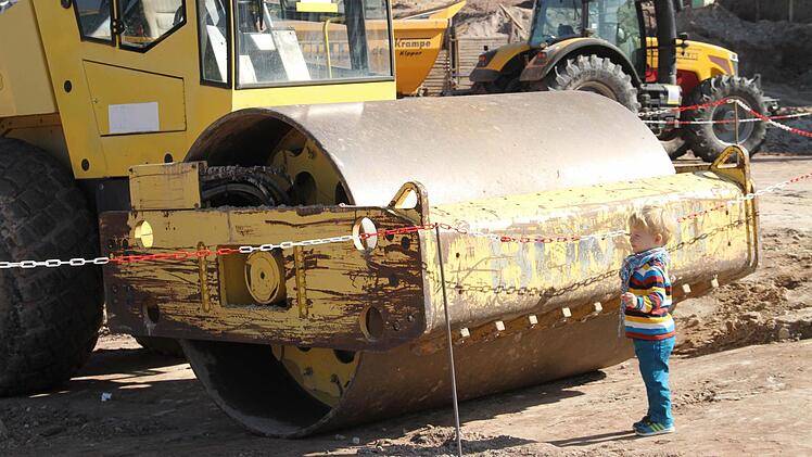 Hier wird viel bewegt: Ein kleiner Gast steht bei der Grundsteinlegung staunend vor den großen Baumaschinen. Foto: Gerda Völk