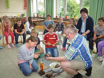 Lara, Hennes und Florian waren von der Riesen-Achatschnecke Wabibio begeistert (vorne von links). Auch von den afrikanischen Abenteuererzählungen von Michael Tonfeld (rechts) waren die Grundschüler fasziniert.  Foto: Karl-Heinz Hofmann