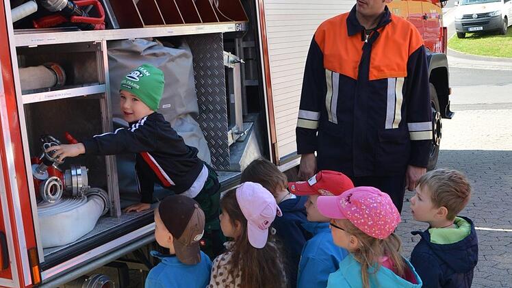Andreas Dietrich erklärt den Kindergartenkindern, was alles in einem Feuerwehrauto transportiert wird. Foto: Björn Hein
