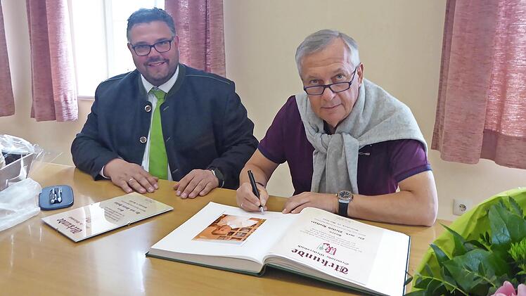 Detlev Hollatz (r.) trägt sich bei Bürgermeister Marco Friepes ins Goldene Buch der Gemeinde Weilersbach ein.