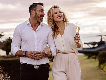 Elegant couple walking outdoors with wine