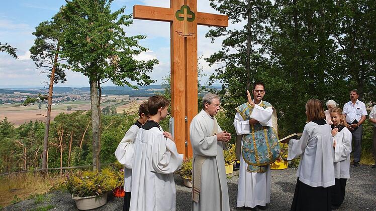 Pfarrer Florian Lehnert segnete am Feiertag "Mariä Himmelfahrt" das neue Kreuz, das der Milzer Bildhauer Dieter Frank entworfen hat. Es steht an einem markanten Punkt im neuen Naturfriedhof und bietet Möglichkeit zur Ruhe. Foto: Friedrich