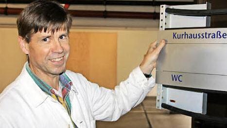 M. Voll von der Haustechnik schraubt die Schilder ab, zumindest ein Teil davon wird in das ehemalige Telekom-Gebäude mitgenommen.