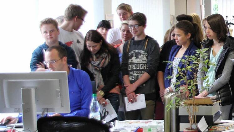 Alexander Löffler (sitzend) erklärt den Gymnasiasten, wie die Ausgabe des nächsten Tags am PC geplant wird. Foto: Marco Meißner