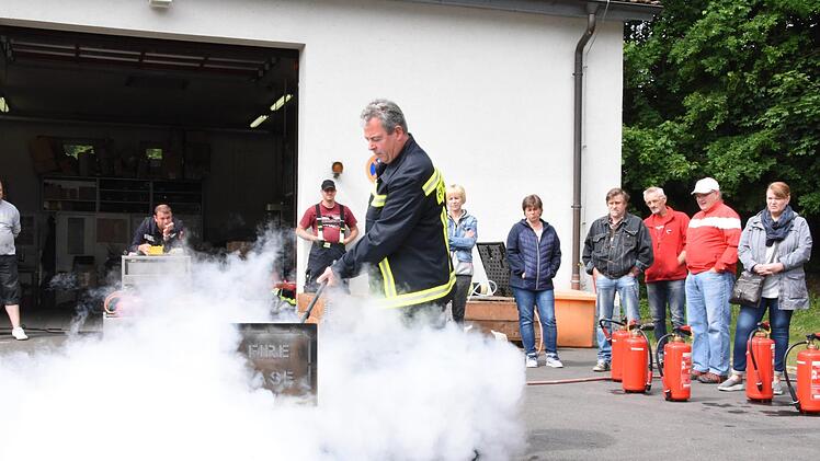 Der Feuerwehrmann führt das Löschen vor.