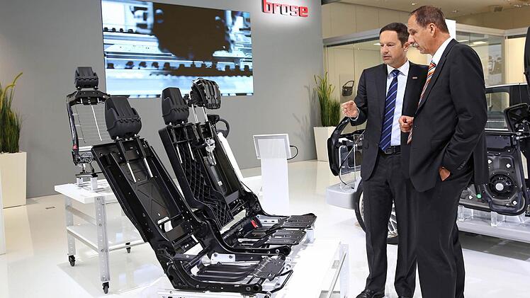 Der Vorsitzende der Brose Geschäftsführung, Jürgen Otto, erklärt Klaus Draeger, Mitglied des Vorstands der BMW AG, am IAA-Stand in Frankfurt die Brose-Rücksitzstruktur. Foto: Brose