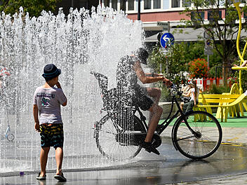 Frau fährt mit Rad durch einen Brunnen