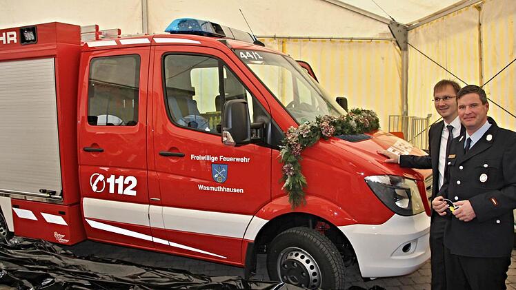 Kommandant Christian Vogel und Bürgermeister Wolfram Thein (von rechts) haben das in schwarzer Folie verpackte Einsatzfahrzeug "Florian Wasmuthhausen 44/1" enthüllt. Foto: Helmut Will