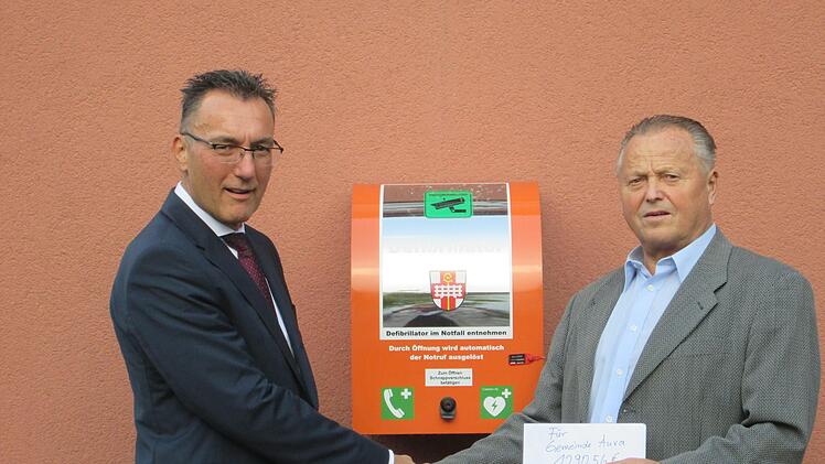 Ein Defibrillator, der bei Herzrhythmusstörungen eingesetzt wird, erstand die Gemeinde Aura für die Spende, die Bürgermeister Thomas Hack (l.) von Alfred Graser entgegennahm.