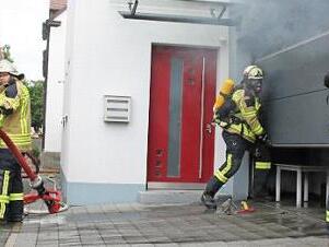 Mit Atemschutz öffnen die Feuerwehrleute das Garagentor.  Foto: Oswald