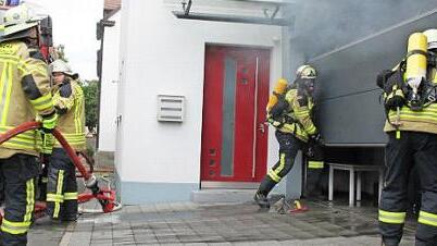 Mit Atemschutz öffnen die Feuerwehrleute das Garagentor.  Foto: Oswald