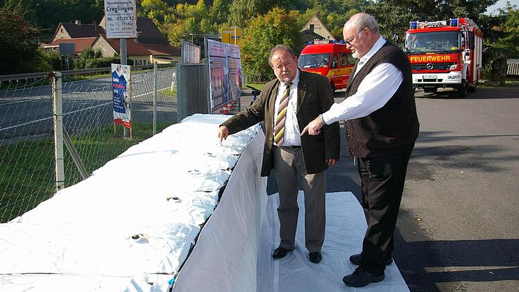 Der Damm hält: Bürgermeister Erich Hegwein und Geschäftsführer Karl Orth begutachten die mit Wasser gefüllte Staumauer von der Seite aus, von der das Hochwasser kommen würde.  Fotos: Tom Müller