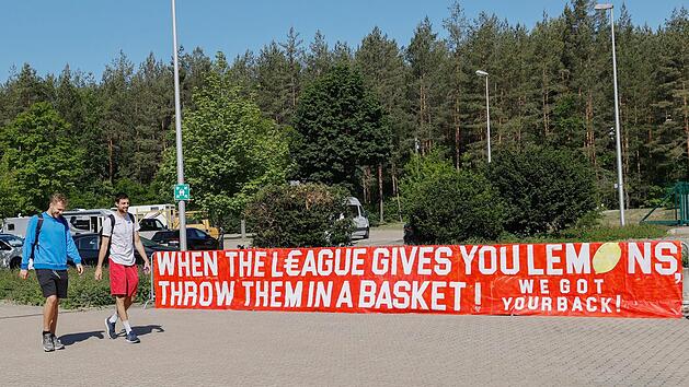 Christian Sengfelder und Mateo Seric laufen an einem Banner vorbei, das die "Sektion S&uuml;dblock" vor dem Trainingscenter Hauptsmoor aufgeh&auml;ngt hat. Darauf steht eine Abwandlung der im Englischen gebr&auml;uchlichen Redewendung "When life gives you lemons, make lemonade" (Wenn das Leben dir Zitronen gibt, mach Limonade draus). Sie bedeutet in etwa, dass man allen Widrigkeiten trotzen soll, und ist als motivierender Ausspruch gedacht.  Foto: Daniel L&ouml;b