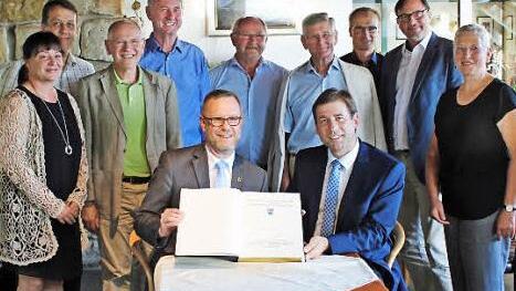 Bezirksbürgermeister Reinhard Naumann (l.) und Landrat Hermann Ulm mit dem Gästebuch im Kreis der Partner.