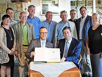 Bezirksb&uuml;rgermeister Reinhard Naumann (l.) und Landrat Hermann Ulm mit dem G&auml;stebuch im Kreis der Partner.