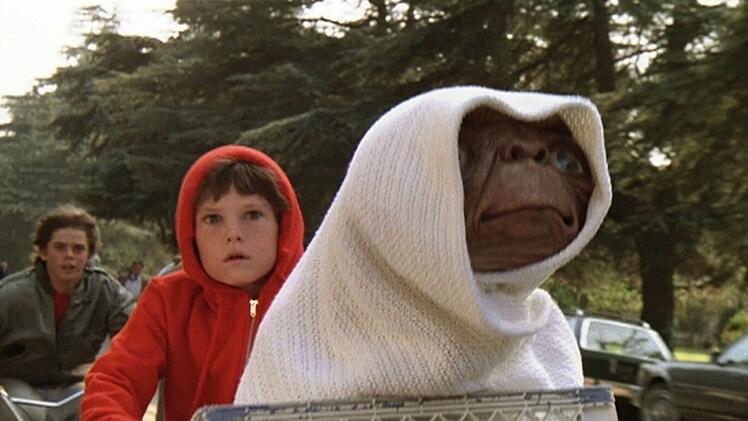 Auch er z&auml;hlte zum (erweiterten) Freundeskreis der Hauptfigur: Tyler (C. Thomas Howell, links) ist dabei, als Elliott (Henry Thomas, Mitte) seinen Freund E.T. auf einem BMX-Rad zu seinem Raumschiff bringt.